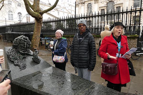 在伦敦街头，学生们正在观看一个由黑色石头制成的大型雕塑