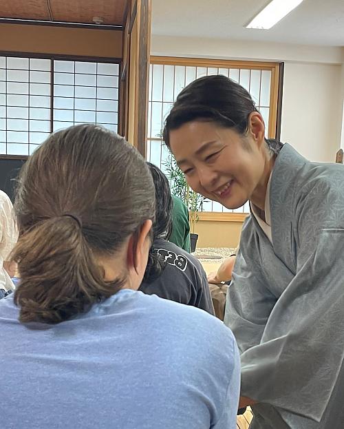 日本ese woman smiling while serving tea to students