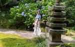 Student in white dress walking down path in 日本ese garden with stone statue in foreground