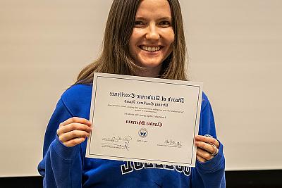 Student 克劳迪娅·谢尔曼 holding the Writing Excellence Award.