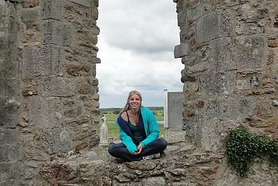 L和mark College student sitting in an archway at Clonmacnoise