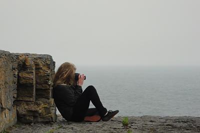 学生坐在莫赫悬崖边拍照