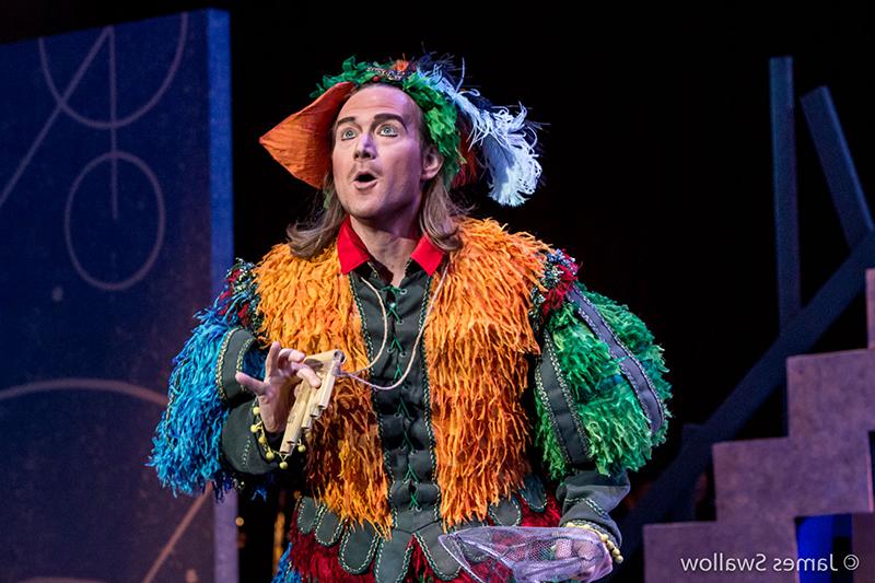 Man singing opera dressed in colorful costume and holding a pan flute